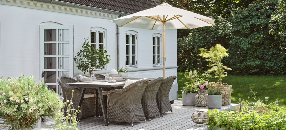 Umbrelă de soare pe terasa din grădină cu masă de grădină și scaune de grădină