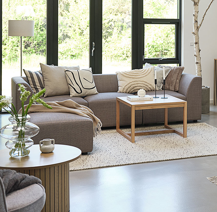 Măsuță de cafea minimalistă în living luminos cu canapea mare și perne decorative
