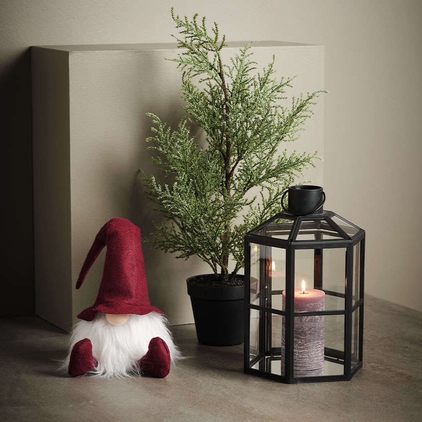 Spiriduș de Crăciun scandinav lângă plantă artificială și lanternă