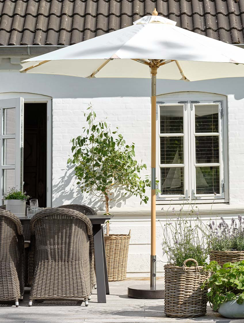 Umbrelă de soare clasică de grădină de culoare albă pe terasă, cu masă de grădină și scaune de grădină