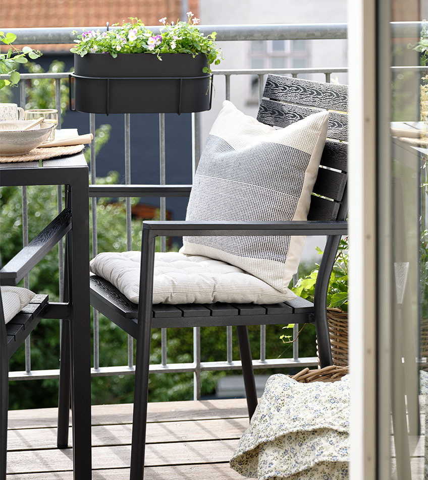 Scaun de grădină negru stivuit cu perne pe balcon