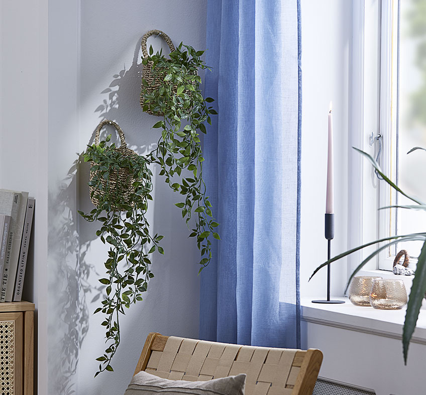 Două coșuri cu plante artificiale agățate pe un perete în sufragerie