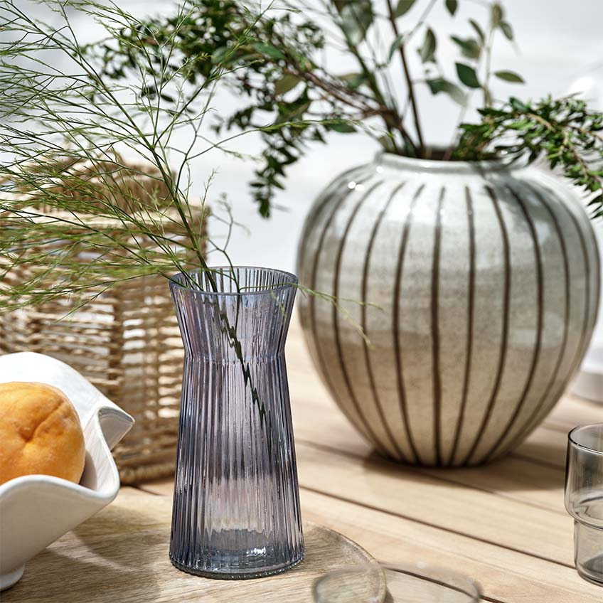 Vaze, un felinar și un bol pe o masă de lemn, pe terasă