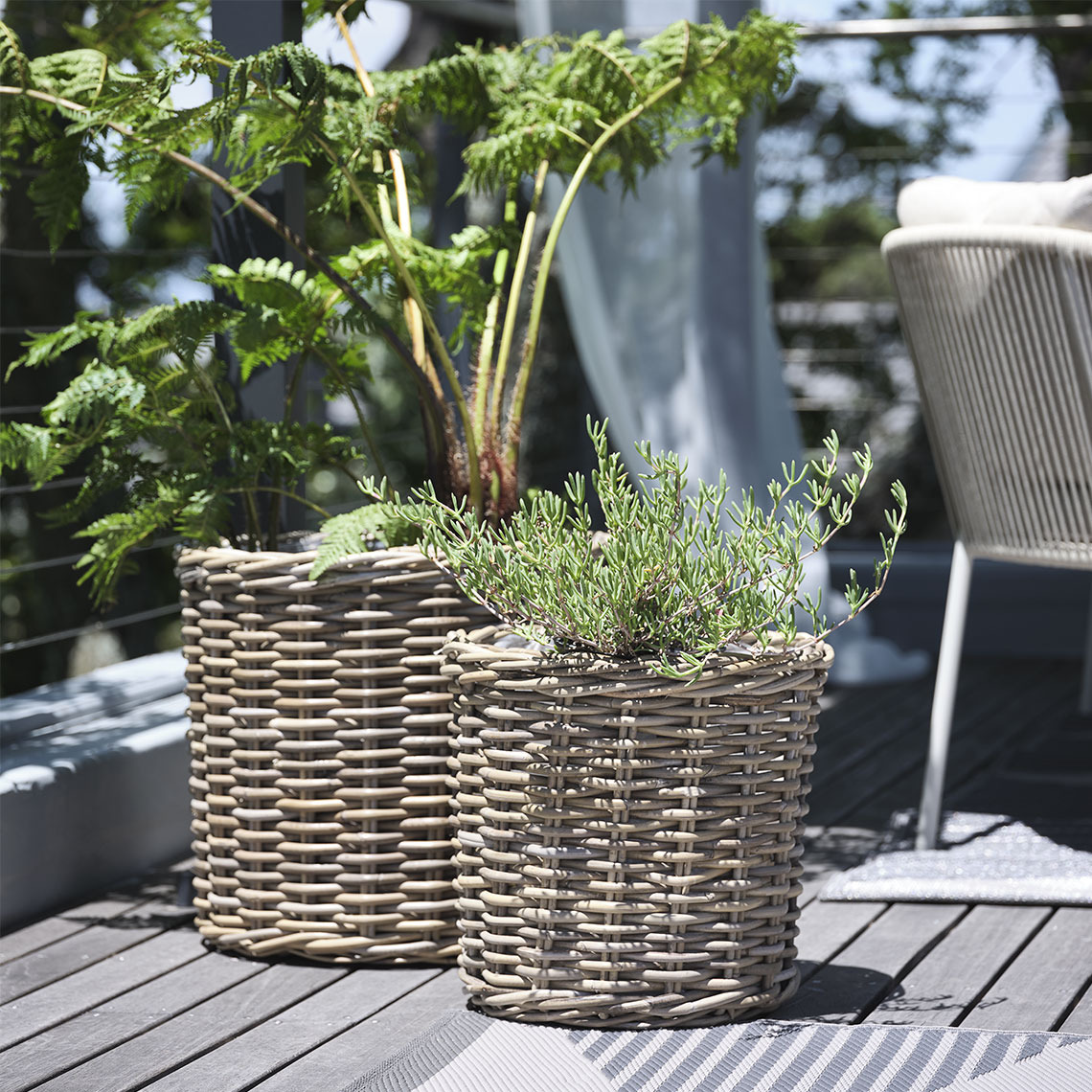 SEGLA ghivece de flori Două ghivece din ratan natur cu plante pe un balcon