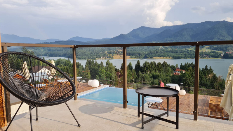 Zonă de relaxare în aer liber, cu fotoliu lounge JYSK, cu vedere spre munți și lac