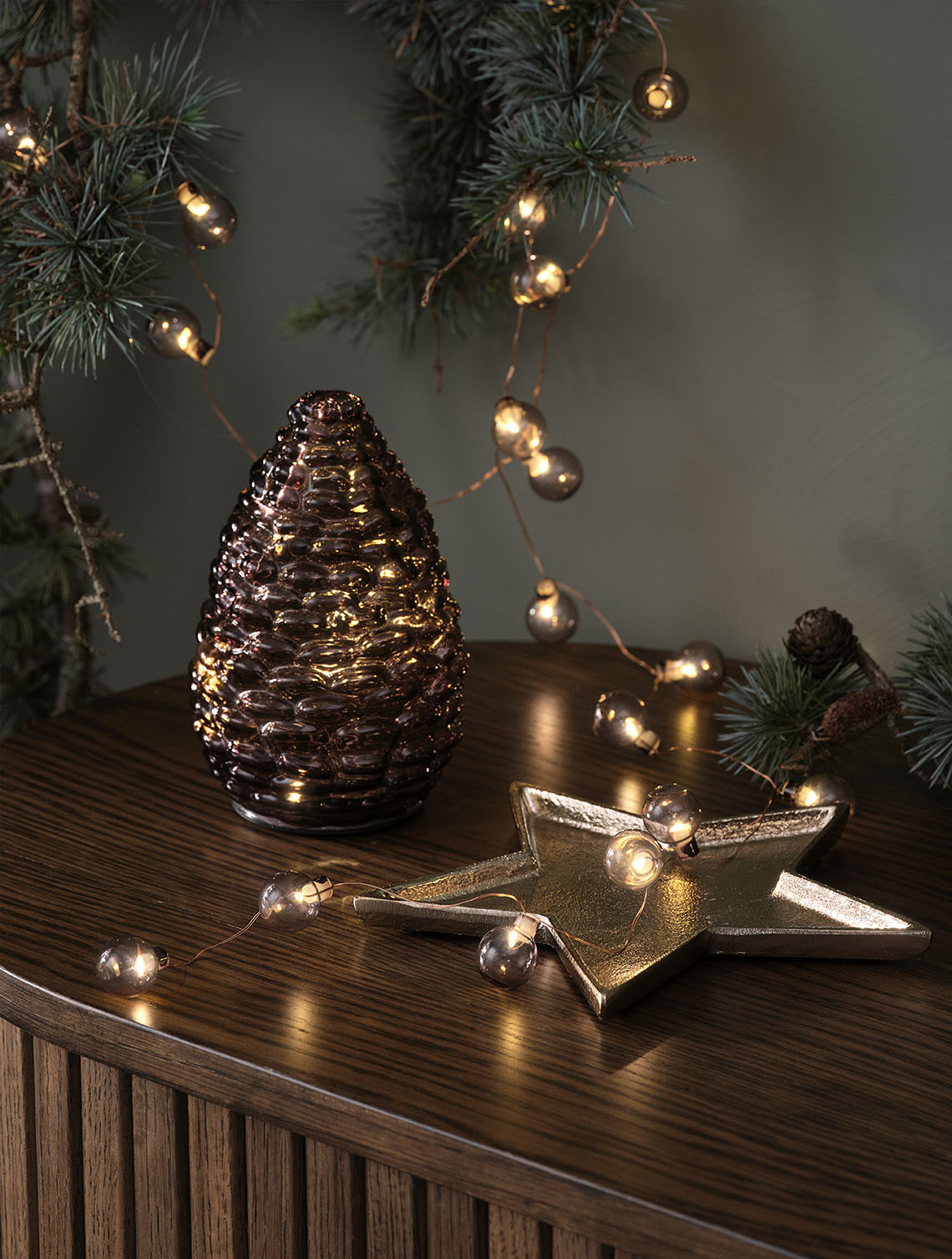 DELLING con de Crăciun și ALV instalație de lumini Decorațiuni luminoase de Crăciun, cum ar fi un con de pin din sticlă și o instalație cu globuri gri pe un bufet