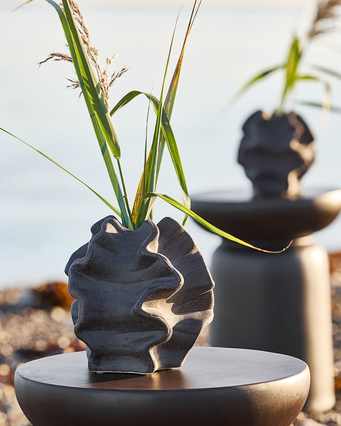 Vaza VILHELM Vază sculpturală pe piedestal lângă o plajă