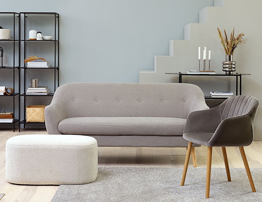 Large, oval footstool in a living room with a sofa and a dining chair