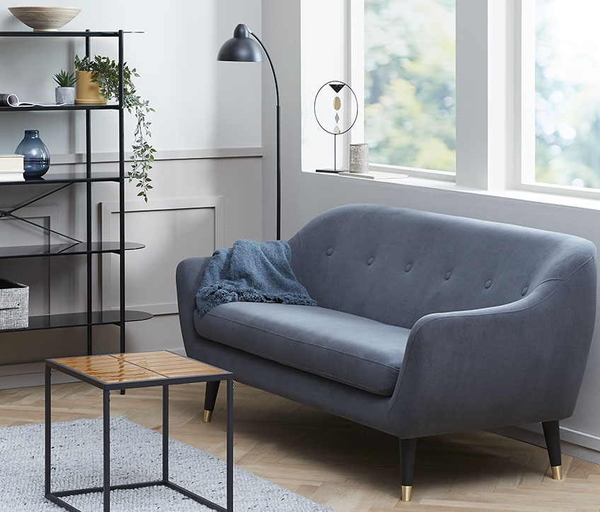 A living room with a small sofa that leaves space for an armchair for reading