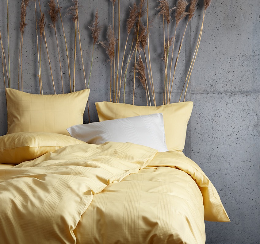 Lenjerie de pat galbenă din 51% poliester reciclat și 49% bumbac satinat într-un dormitor 