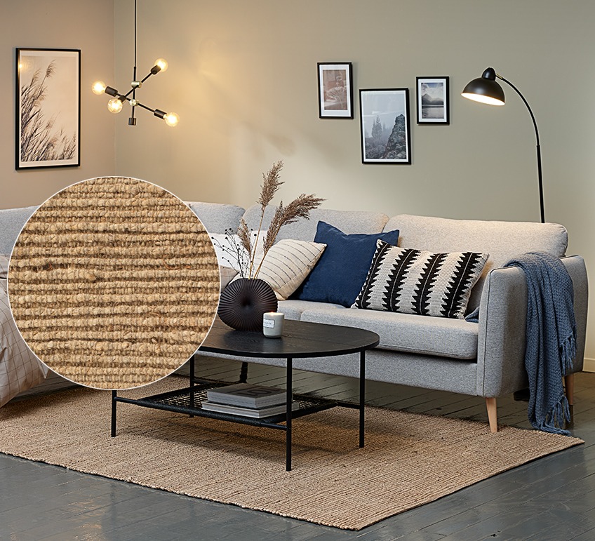 Camera de zi cu o canapea gri și un covor mare din iută sub o măsuță de cafea