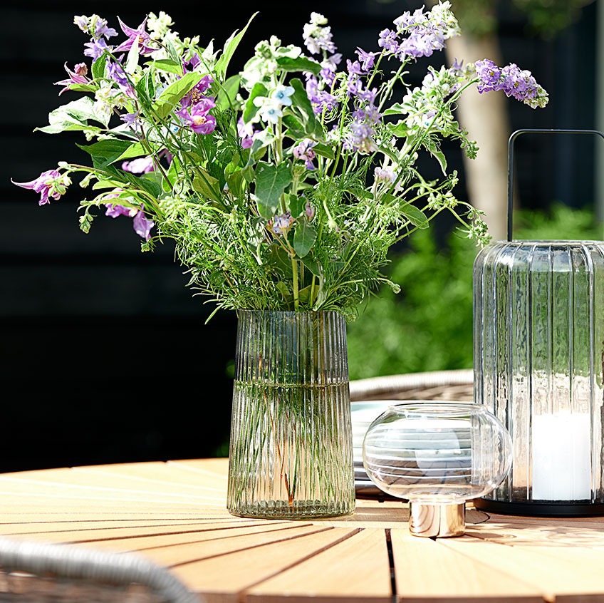 Glass vase and lanterns on a round garden table 