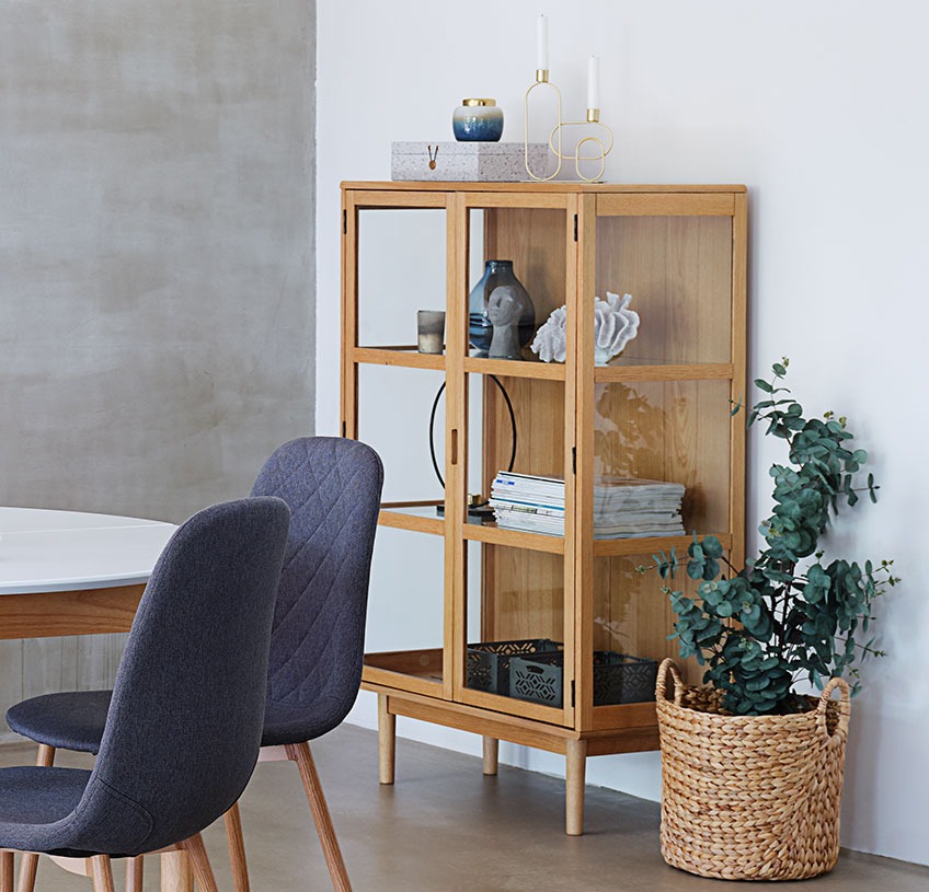 Glass cabinet with shelves out of glass against a white wall in a dining room 