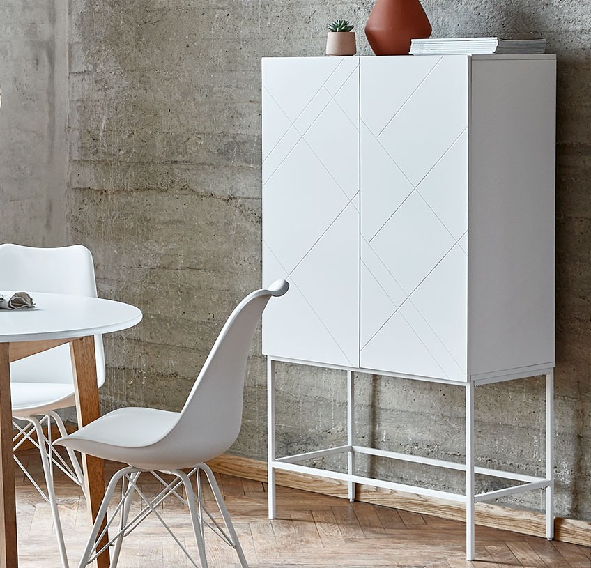 White cabinet with patterned doors in a dining room with white dining chairs  