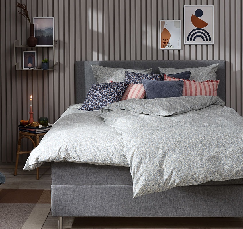 CAMILLE bed linen and JUNGHOLM stool Bedroom with blue floral bed linen and decorative cushions in blue and rose colours