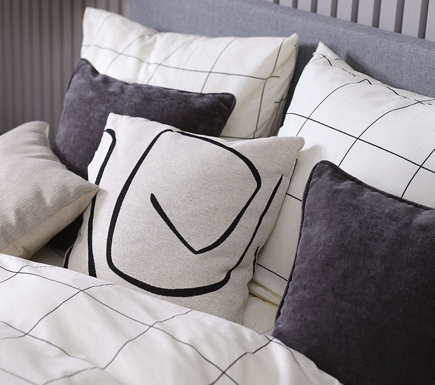 CRISTA bedlinen, LILJE beige cushion, HVITVEIS and HORNFIOL grey decorative cushions Bedroom with white and black bed linen and black and with decorative cushions