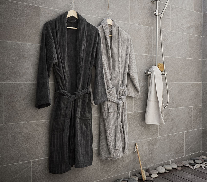 Dark grey TOLLARP bathrobe, light grey BULLMARK bathrobe, SORUNDA towel and VALJE bath brush Bathroom with bathrobes, white towel and bath brush