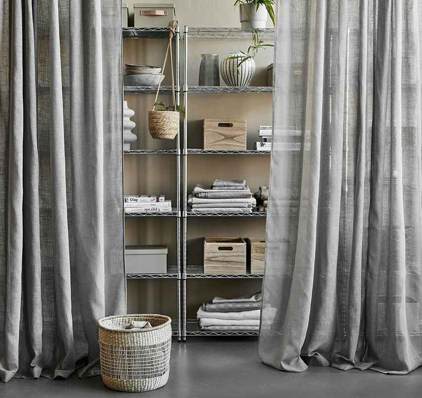 Shelving unit in metal with grey sheer curtains in front