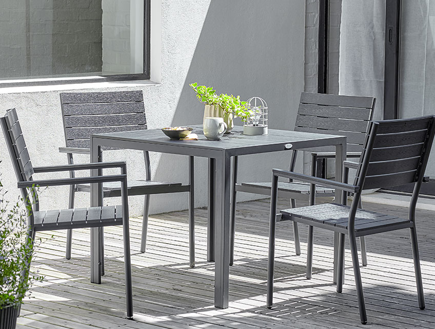 Square garden table and four stacking chairs on a sunny patio 